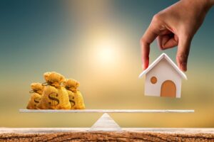 Graphic of scales, money bags on one end, a house being placed on the other