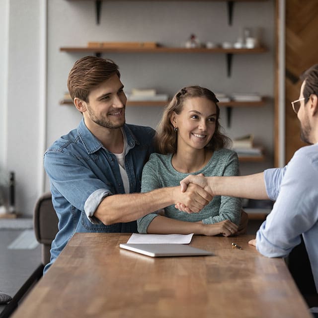 Young couple shaking hands with mortgage broker