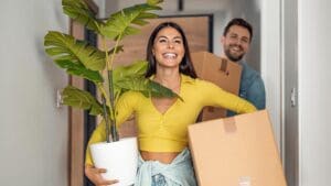 Young couple moving in new home. Couple is having fun with cardboard boxes in new house at moving day.