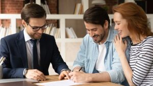 Couple signing paperwork with broker