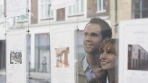 Closeup of a young couple looking through window at estate agents