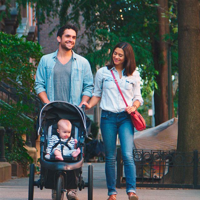 Family with stroller walking in front of Brownstones